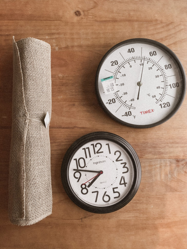 Image of a roll of burlap, a round thermometer, and a clock. 