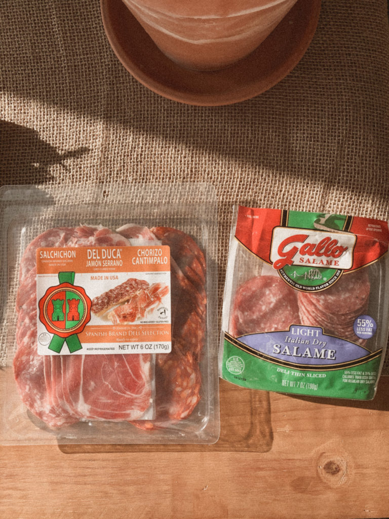 Two packages of salami and prosciutto meat on the table. 