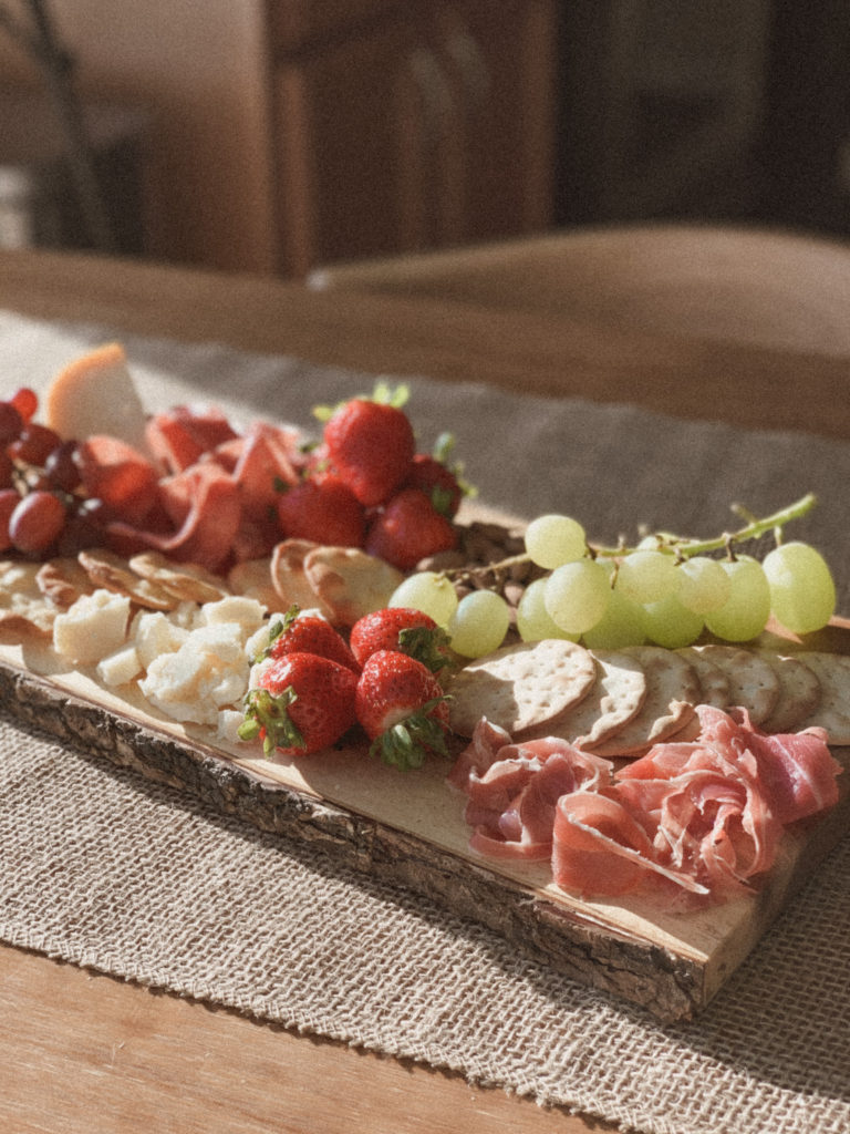 Cheeseboard with meats, fruit, crackers, and nuts.