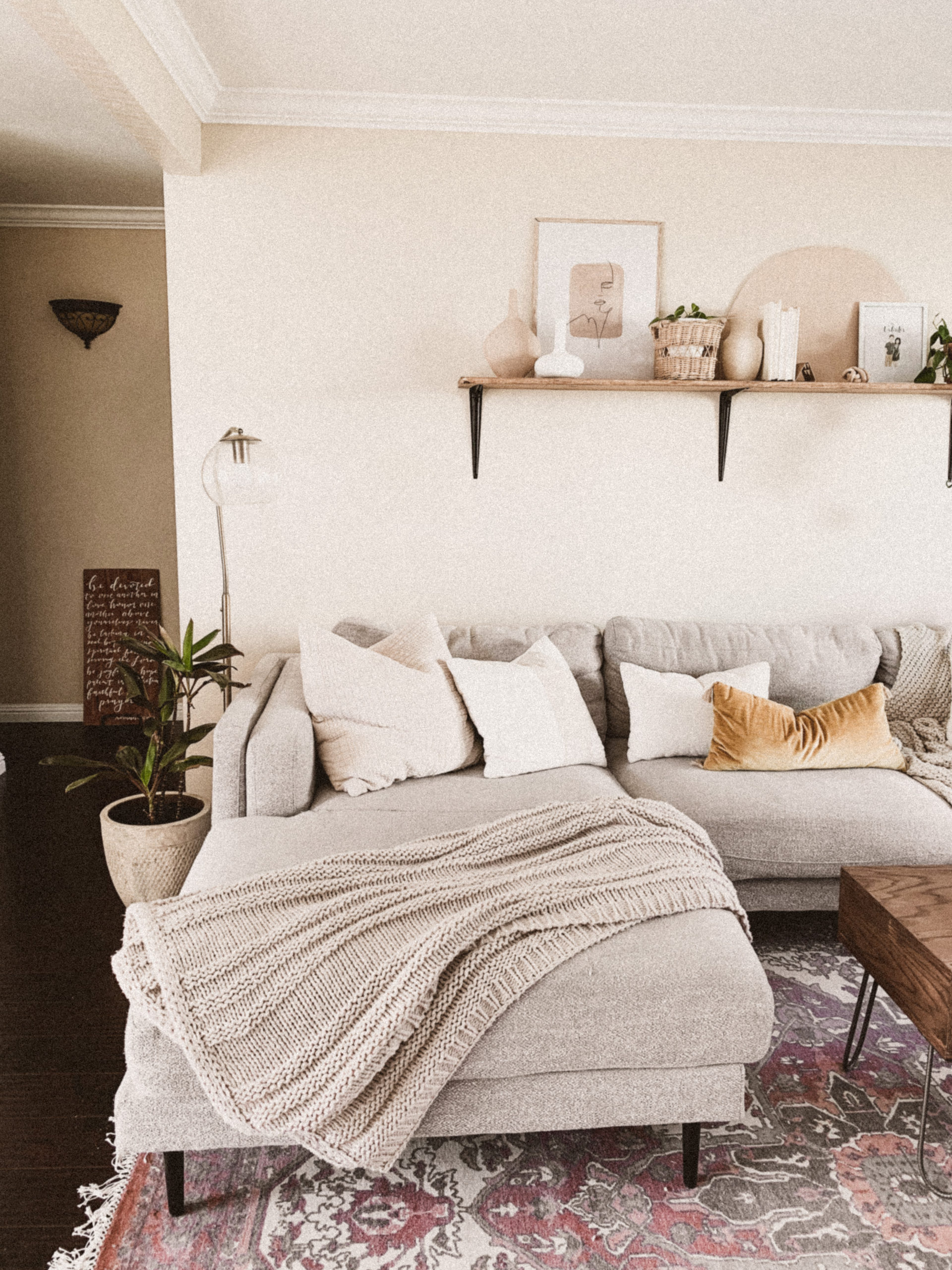 Mid century modern living room with wood shelf above it. Plants, books, and other boho decor accent it.