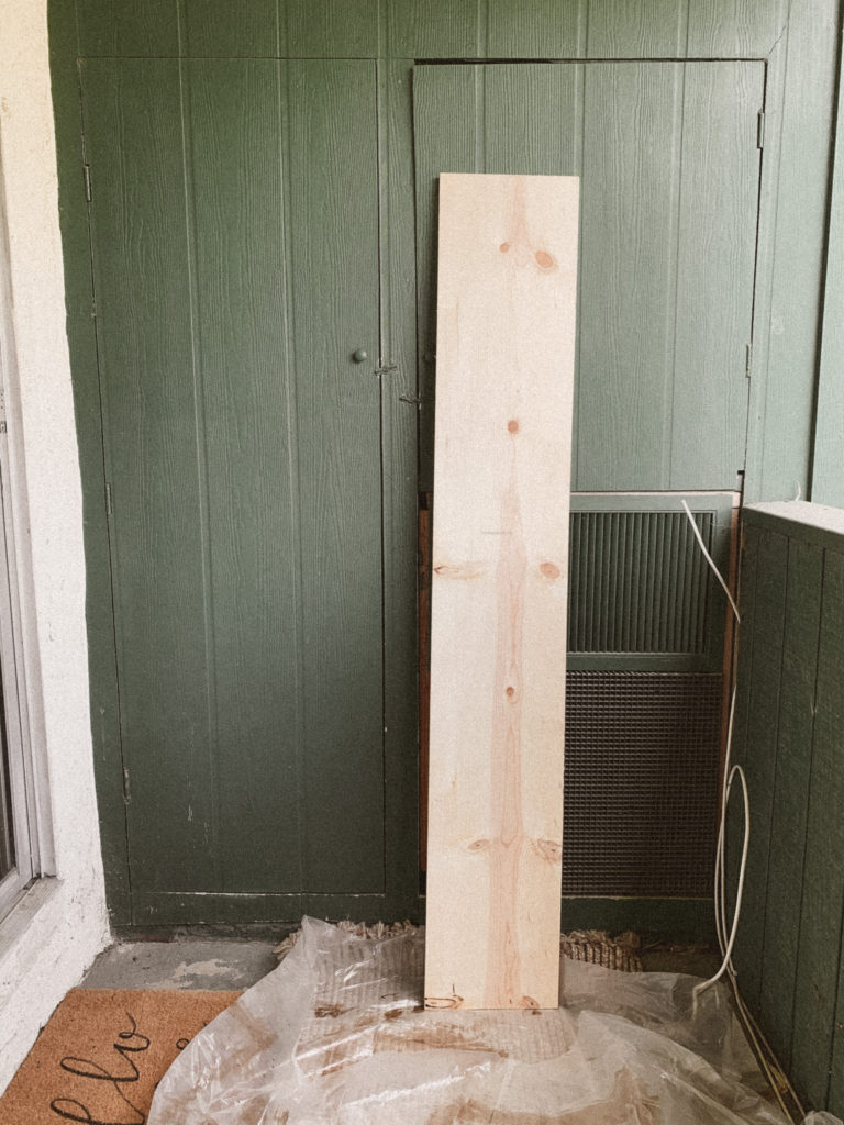 Unfinished piece of pine leaning against a green balcony wall. 