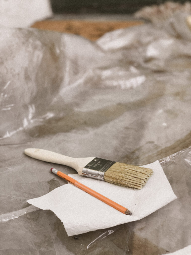 Close up of staining brush and pencil laid out on a paper towel. 