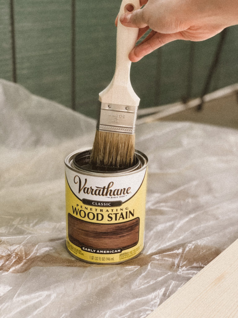 Staining brush dipping into stain can. 