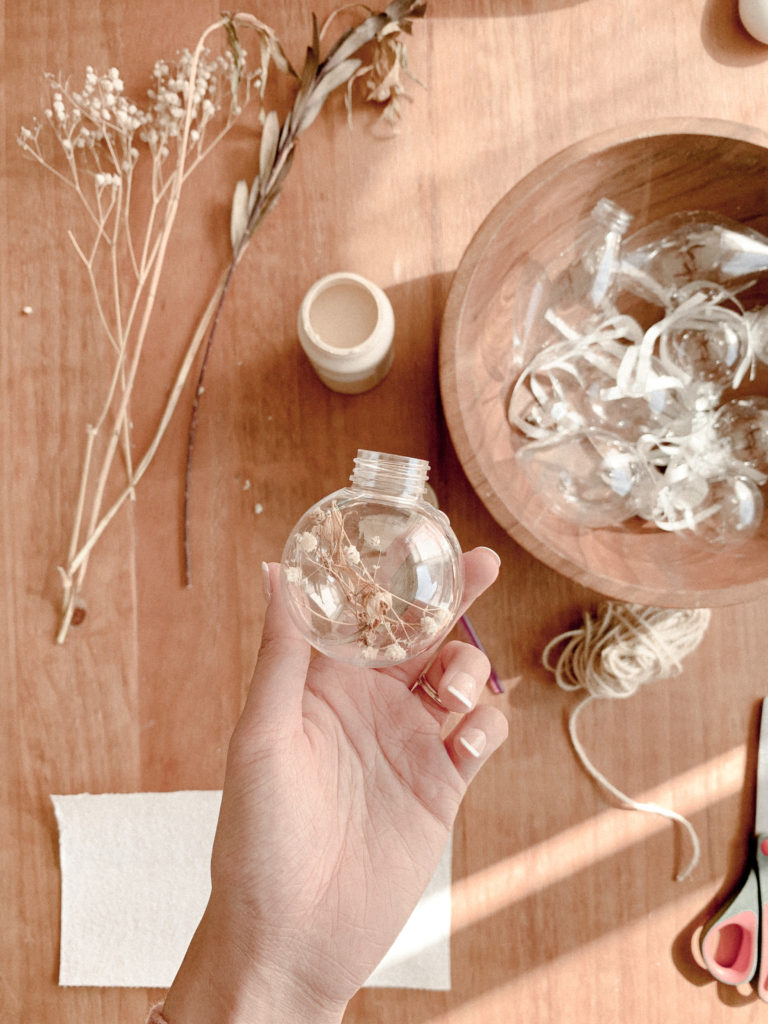 Hand holding up floral-filled clear ornament.