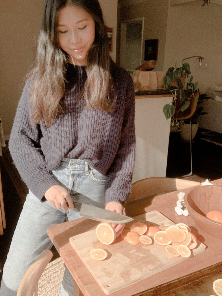 Girl cutting oranges into thin slices.