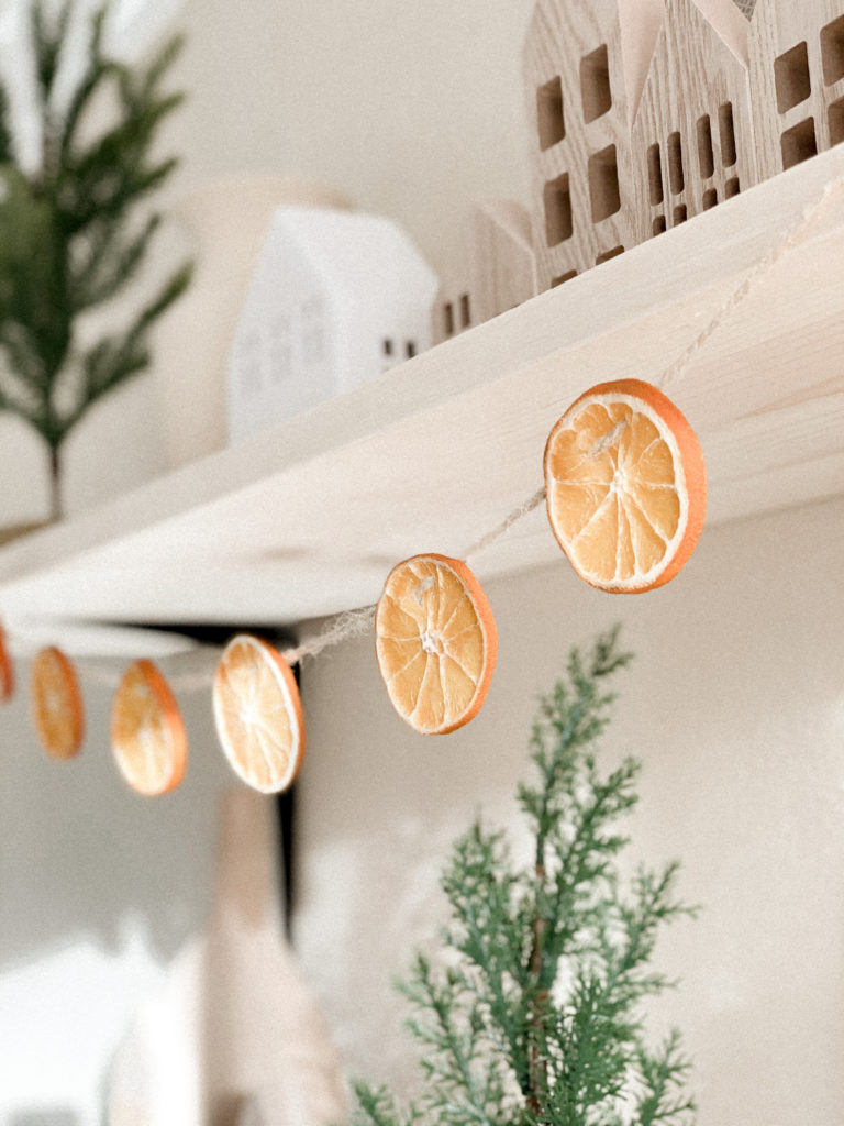 Close up of orange garland hanging from wood shelf. 