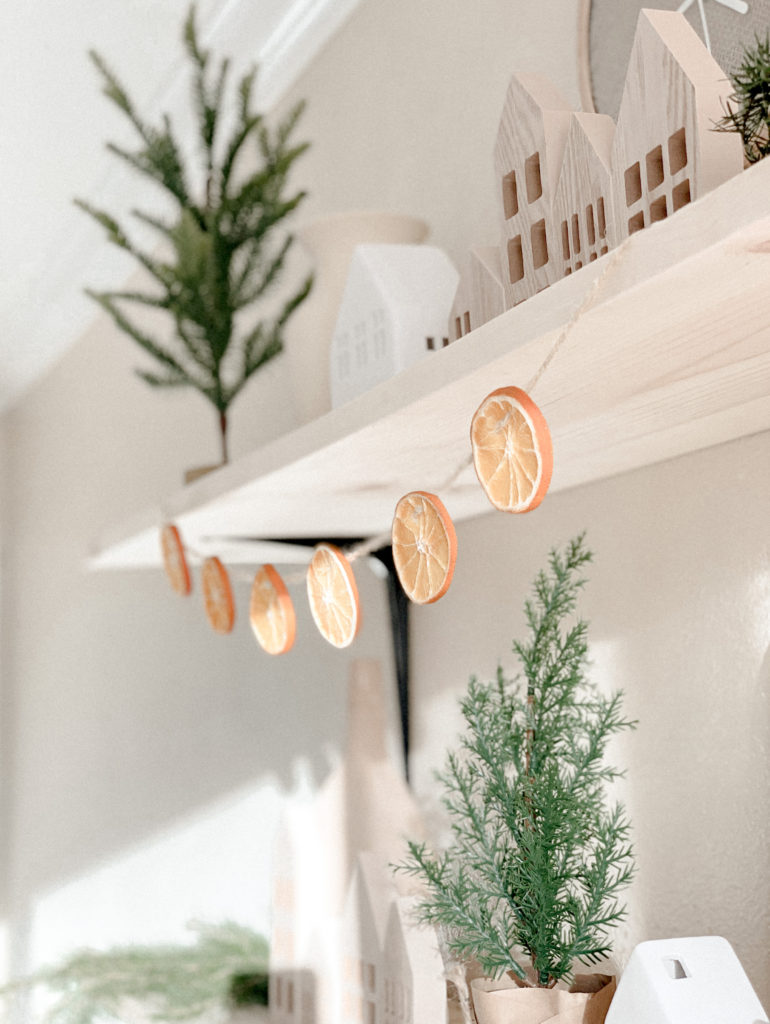 Close up of orange garland hanging from pine wood shelf.