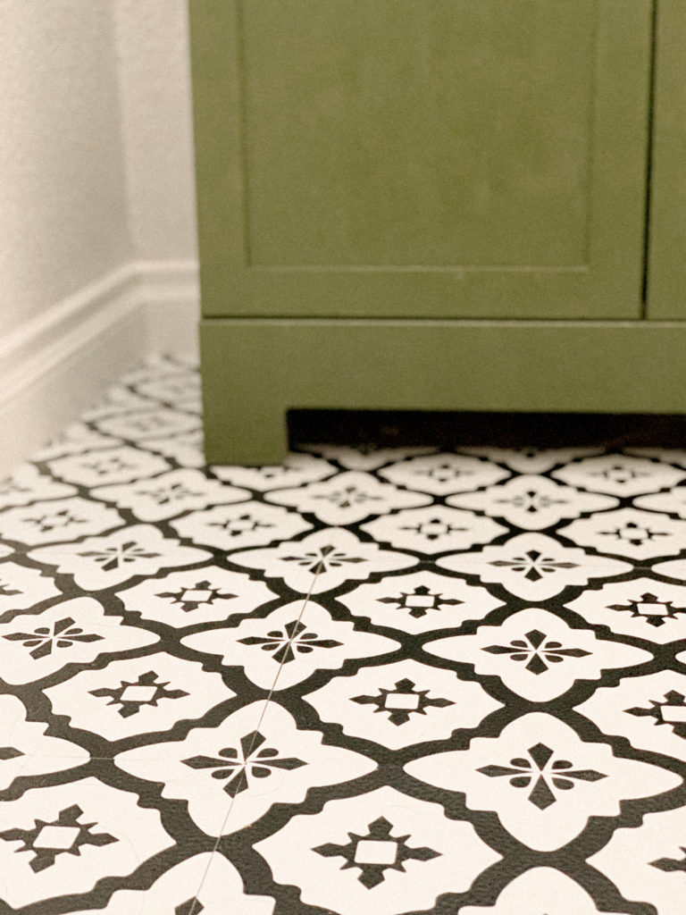 Close up of stick and peel tiles on floor in front of green vanity. 