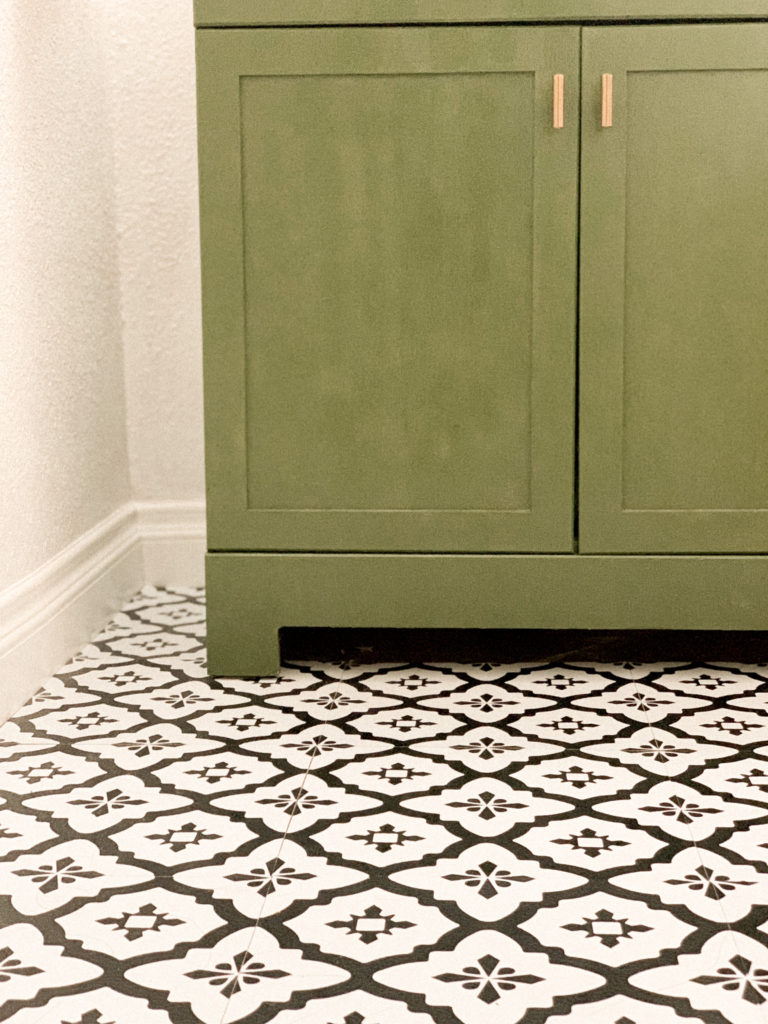 Medium close up of stick and peel tiles in front of dark green vanity. 