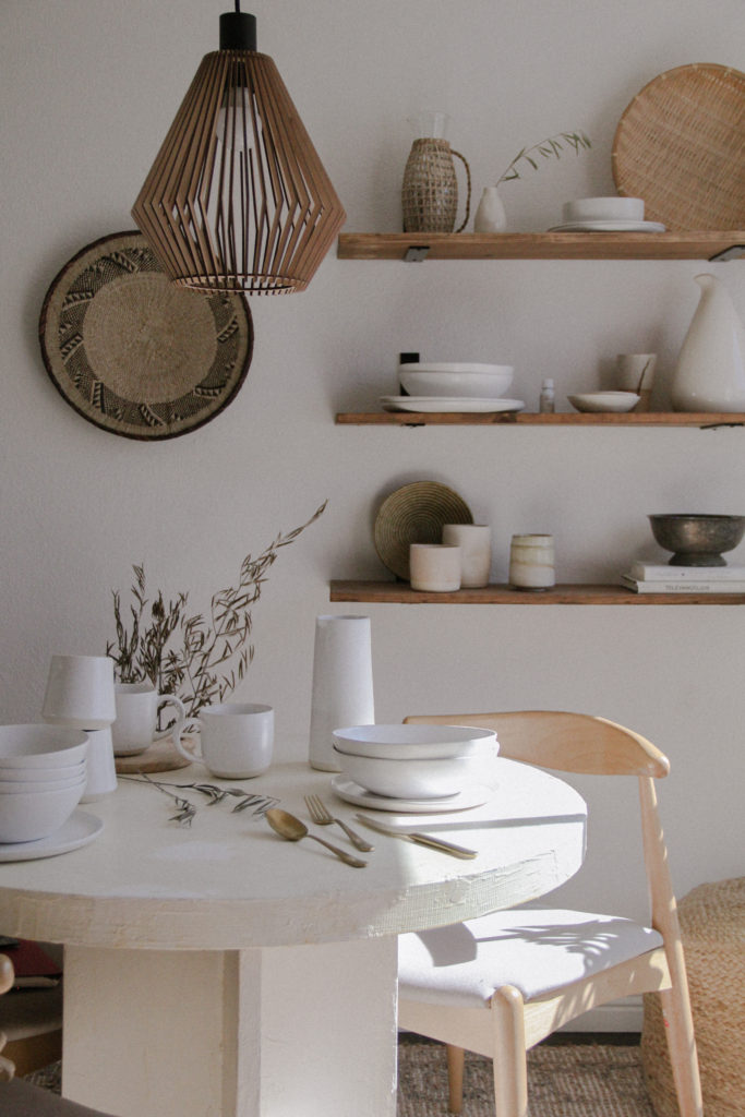 Neutral, minimal dinnerware from Fable on dining table and wood shelves.